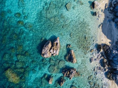Tropea sahilinin hava manzarası, kristal berrak su ve sahilde ortaya çıkan kayalar. Calabria, İtalya. Yüzücüler, suda yüzen banyocular. Calabria kıyıları