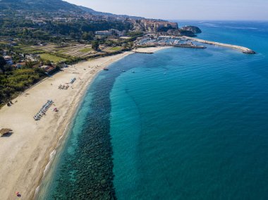 Tropea sahilinin hava manzarası, kristal berrak su ve sahilde ortaya çıkan kayalar. Calabria, İtalya. Yüzücüler, suda yüzen banyocular. Calabria kıyıları