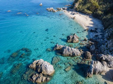 Tropea sahilinin hava manzarası, kristal berrak su ve sahilde ortaya çıkan kayalar. Calabria, İtalya. Yüzücüler, yüzenler. Calabria kıyıları.
