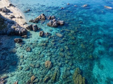 Tropea sahilinin hava manzarası, kristal berrak su ve sahilde ortaya çıkan kayalar. Calabria, İtalya. Yüzücüler, yüzenler. Calabria kıyıları.