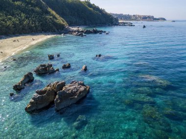 Tropea sahilinin hava manzarası, kristal berrak su ve sahilde ortaya çıkan kayalar. Calabria, İtalya. Yüzücüler, yüzenler. Calabria kıyıları.