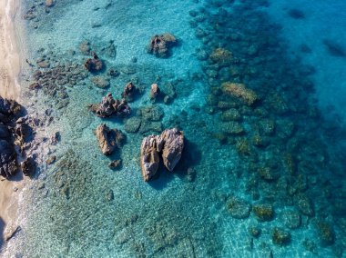 Tropea sahilinin hava manzarası, kristal berrak su ve sahilde ortaya çıkan kayalar. Calabria, İtalya. Yüzücüler, yüzenler. Calabria kıyıları.