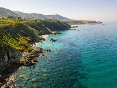 Tropea sahilinin hava manzarası, kristal berrak su ve sahilde ortaya çıkan kayalar. Calabria, İtalya. Yüzücüler, yüzenler. Calabria kıyıları.