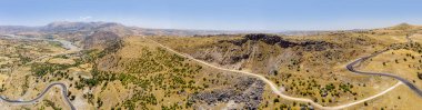Adiyaman ilinin Kahta ilçesinin Taslica köyü yakınlarındaki Katha nehri yakınlarındaki Kahta Sincik Yolu 'nun havadan görüntüsü. Çevrelerinde arabalar ve araçlar olan dolambaçlı yollar.