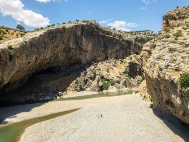 Chabinas 'ın geniş ve neredeyse kuru nehir yatağının üzerinde tarih öncesi mağaralar bulunan vadi panoramik manzarası. Yazın, Nemtur Dagi yoluna yakın, Cendere deresi. Türkiye