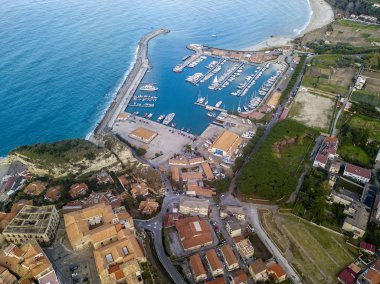 İtalya, Calabria, Tropea Limanı 'na demirlemiş teknelerin hava görüntüsü. Denize bakan evler. Ufuktaki kumsal. İtalyan kıyıları
