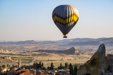 Kapadokya, Türkiye, Avrupa, 07 / 08 / 2019: Eski Cavusin kasabasının tepesindeki 5. yüzyıldan kalma bir mağara kilisesi olan Vaftizci Yahya (Cavusin Kalesi) kilisesinde şafaktan sonra yüzen sıcak hava balonu