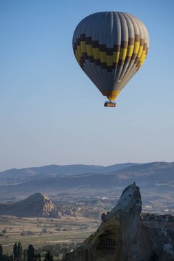 Kapadokya, Türkiye, Avrupa, 07 / 08 / 2019: Orta Anadolu 'nun tarihi bölgesinde yer alan eski Cavusin kasabasının tepesindeki 5. yüzyıldan kalma bir mağara kilisesi olan Vaftizci Yahya (Cavusin Kalesi) kilisesinde şafaktan sonra yüzen sıcak hava balonu