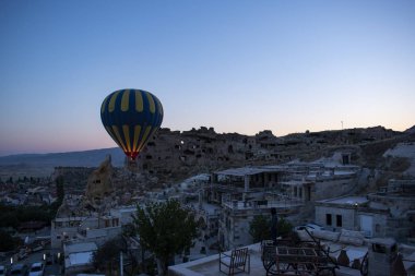 Kapadokya, Türkiye, 07 / 08 / 2019: Orta Anadolu 'nun tarihi bölgesindeki eski Cavusin kasabasının tepesindeki ünlü 5. yüzyıl mağara kilisesi olan Vaftizci Yahya (Cavusin kalesi) kilisesinde şafak vakti yüzen sıcak hava balonu