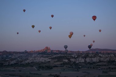 Kapadokya, Türkiye, Avrupa, 07 / 08 / 2019: Orta Anadolu 'nun tarihi bölgesinin tarihi ve ünlü kenti Uchisar' ın havadan görünüşü, olağanüstü doğal harikalara sahip, şafakta soluk kesici pembe gökyüzünde yüzen sıcak hava balonları