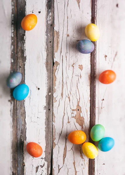 Ostern: bunte Ostereier auf rustikal bemaltem Tisch verstreut — Stockfoto