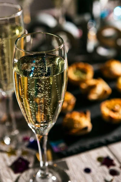 New Year: Glass of Champagne with Party Food Behind — стоковое фото
