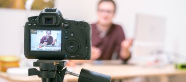 Evde video blogcusu: Tripodun üzerindeki kamera genç bir adamı çekiyor