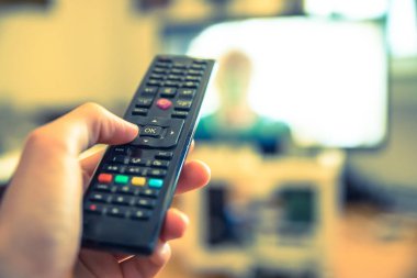 TV uzaktan denetim ön planda, bulanık arka planda tv.