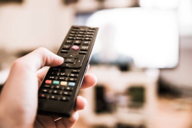 TV uzaktan denetim ön planda, bulanık arka planda tv.