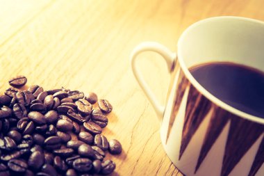 Taze kavrulmuş kahve çekirdekleri ve kupa ahşap masa, arka plan dokusu. 