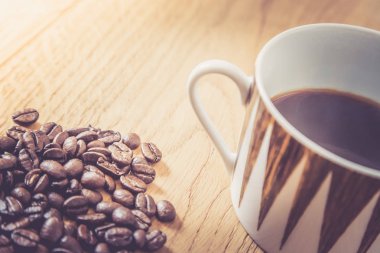 Taze kavrulmuş kahve çekirdekleri ve kupa ahşap masa, arka plan dokusu. 