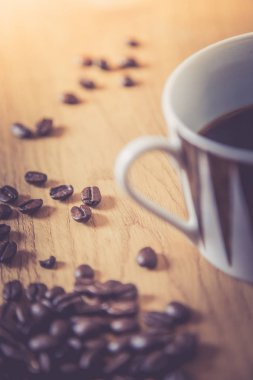 Taze kavrulmuş kahve çekirdekleri ve kupa ahşap masa, arka plan dokusu. 