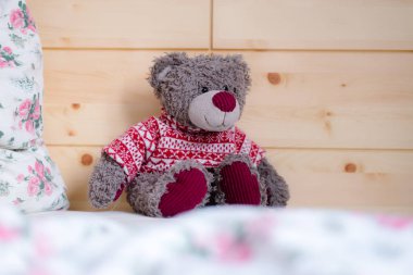 Tatlı oyuncak ayıcık yatakta oturuyor, sabah uyanıyor.