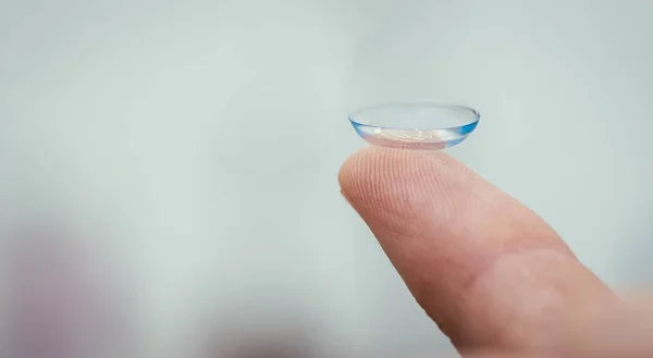 Close up  contact lens on a man\'s finger. Text space.