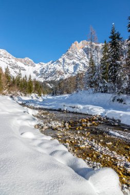 Idyllic kış manzarası: çarpıcı dağ sıraları, güzel nehir, karlı ağaçlar ve mavi gökyüzü