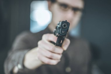 Soyguncu ya da suçlu siyah bir silahla nişan alıyor, yüzü bulanık.