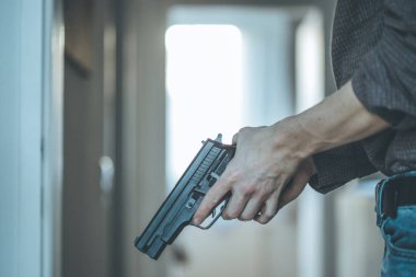 Gizli polis memuru elinde siyah bir silah tutuyor, vurmaya hazır.