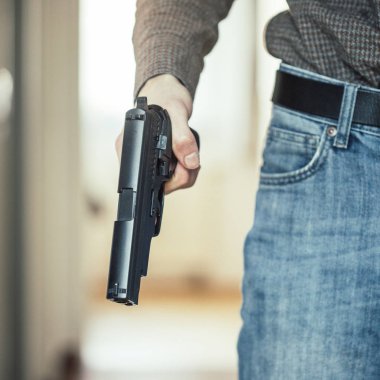 Gizli polis memuru elinde siyah bir silah tutuyor, vurmaya hazır.