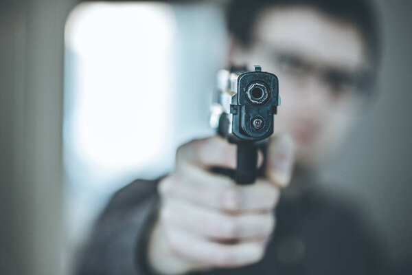 Robber or criminal is aiming with a black gun, blurry face