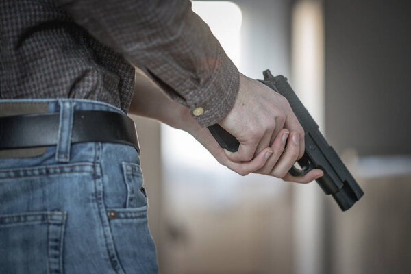 Undercover police agent is holding a black weapon in his hand, ready for shoot