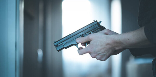 Undercover police agent is holding a black weapon in his hand, ready for shoot