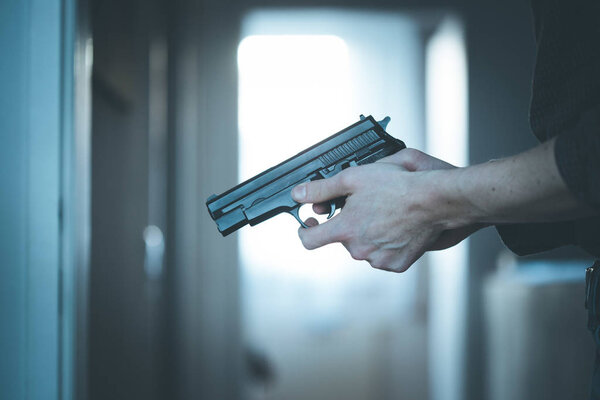 Undercover police agent is holding a black weapon in his hand, ready for shoot