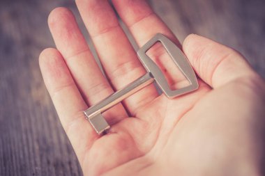 Genç erkek el ele tutuşuyor ve arka planda eski anahtar, tahta masa.