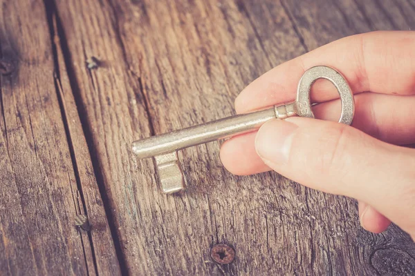 Jonge Mannelijke Hand Houdt Oude Sleutel Houten Bureau Achtergrond — Stockfoto