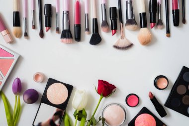 Makyaj fırçaları ve diğer aksesuarlar. Ruj, rimel, oje, göz farı, pudra, kirpik ve fondöten. Makyaj ürünleri beyaz arka planda, üst görünümde. 