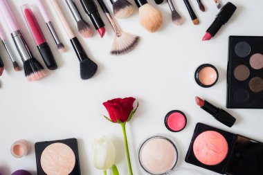 Makyaj fırçaları ve diğer aksesuarlar. Ruj, rimel, oje, göz farı, pudra, kirpik ve fondöten. Makyaj ürünleri beyaz arka planda, üst görünümde. 
