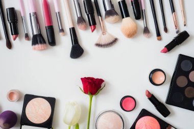 Makyaj fırçaları ve diğer aksesuarlar. Ruj, rimel, oje, göz farı, pudra, kirpik ve fondöten. Makyaj ürünleri beyaz arka planda, üst görünümde. 