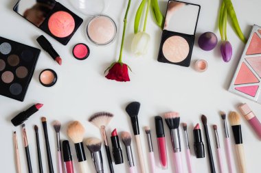 Makyaj fırçaları ve diğer aksesuarlar. Ruj, rimel, oje, göz farı, pudra, kirpik ve fondöten. Makyaj ürünleri beyaz arka planda, üst görünümde. 