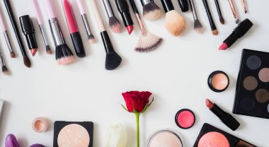 Makyaj fırçaları ve diğer aksesuarlar. Ruj, rimel, oje, göz farı, pudra, kirpik ve fondöten. Makyaj ürünleri beyaz arka planda, üst görünümde. 