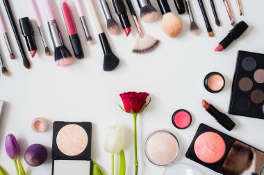 Makyaj fırçaları ve diğer aksesuarlar. Ruj, rimel, oje, göz farı, pudra, kirpik ve fondöten. Makyaj ürünleri beyaz arka planda, üst görünümde. 