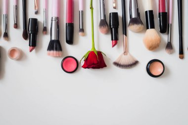 Makyaj fırçaları ve diğer aksesuarlar. Ruj, rimel, oje, göz farı, pudra, kirpik ve fondöten. Makyaj ürünleri beyaz arka planda, üst görünümde. 