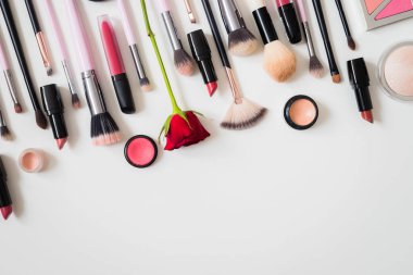 Makyaj fırçaları ve diğer aksesuarlar. Ruj, rimel, oje, göz farı, pudra, kirpik ve fondöten. Makyaj ürünleri beyaz arka planda, üst görünümde. 
