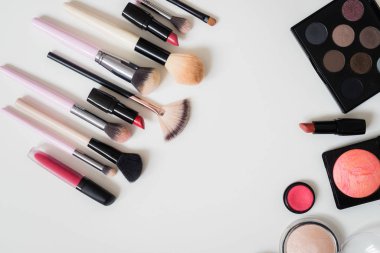 Makyaj fırçaları ve diğer aksesuarlar. Ruj, rimel, oje, göz farı, pudra, kirpik ve fondöten. Makyaj ürünleri beyaz arka planda, üst görünümde. 