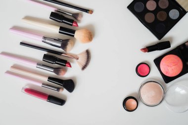 Makyaj fırçaları ve diğer aksesuarlar. Ruj, rimel, oje, göz farı, pudra, kirpik ve fondöten. Makyaj ürünleri beyaz arka planda, üst görünümde. 