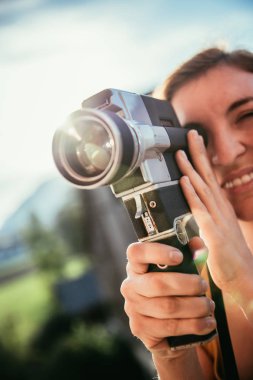Kız bir film çekiyor, klasik eski bir film kamerası.