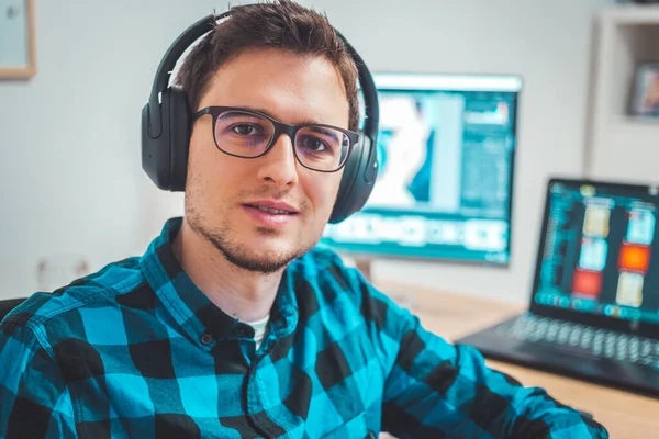 Young Caucasian man with headphones sitting on his workplace, entrepreneur