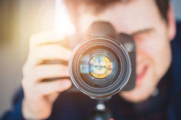 Фотограф стоит за профессиональной камерой с телеобъективом на штативе. Солнечный луч
.