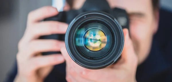 Fotoğrafçı, profesyonel bir kameranın arkasında elinde telefon lensleriyle tripodun üzerinde duruyor.