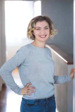 Sarışın, kıvırcık saçlı tatlı genç kadın yeni evinden memnun. 