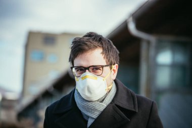 Dışarıda solunum maskeli genç bir adam. Flue ve corona mevsimi